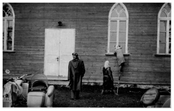 Emmaste Nurste palvemaja akna taga. Mootorratturi riietes Kaljo Järva, ca 1960.-1970. aastatel. Foto: R. Luha erakogu.